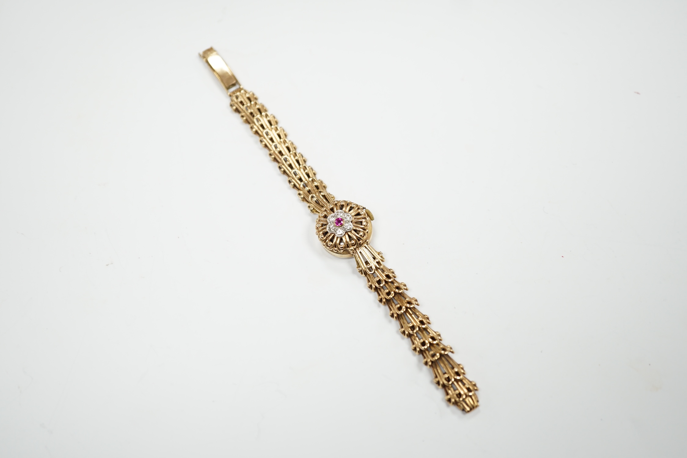A lady's yellow metal manual wind bracelet watch, the dial with ruby and diamond cluster set hinged cover, overall length 16.3cm